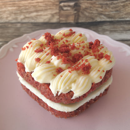 Red velvet cake with cream cheese frosting on a pink plate